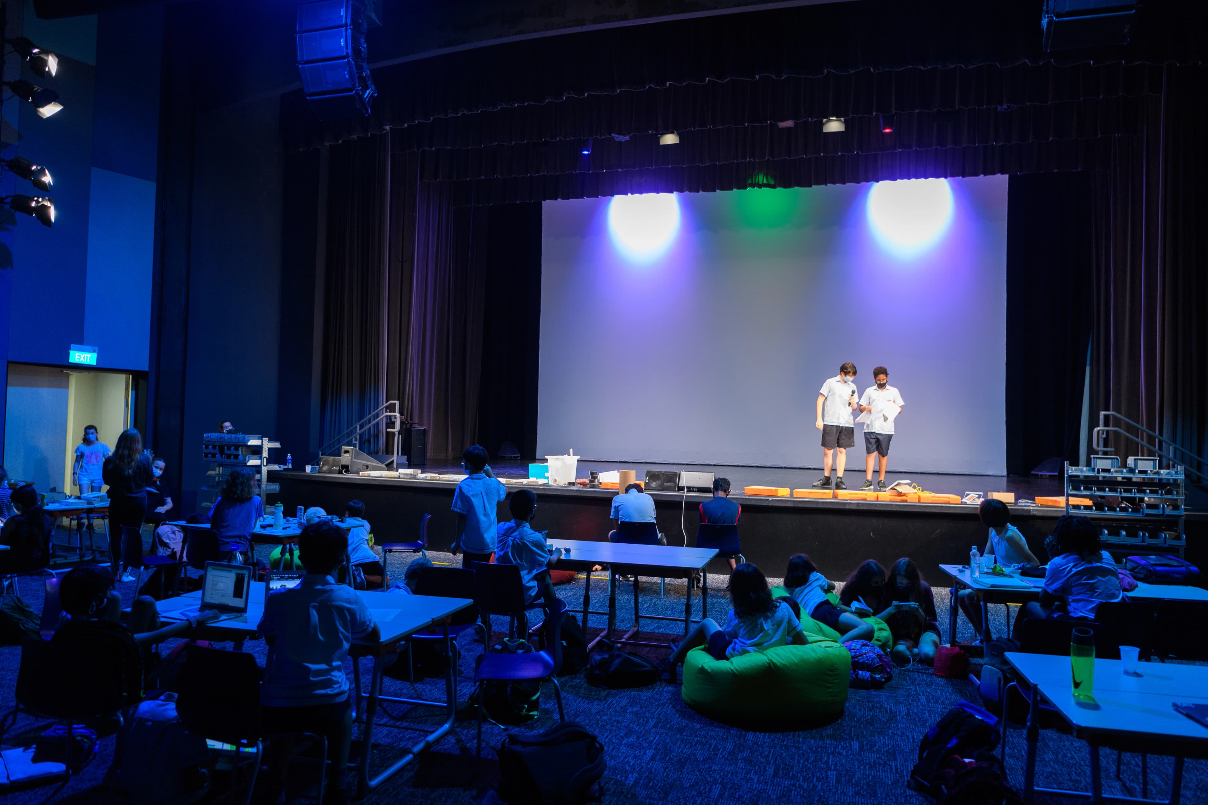 Dark room with a stage and students sitting below